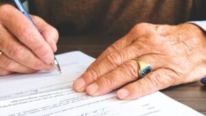 man signing a trust with a ring on finger