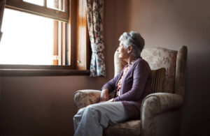 Elderly woman sitting and looking out the window.
