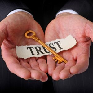Hands holding a vintage key labeled 'TRUST'