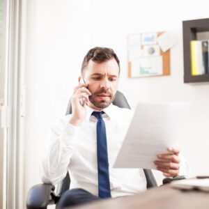 Man in business attire on the phone while reading a document