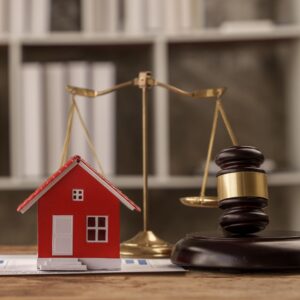 Mini house, gavel, and scales on legal desk