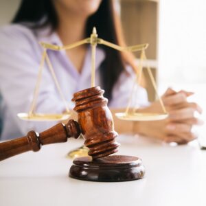 Gavel and scales near female client's folded hands