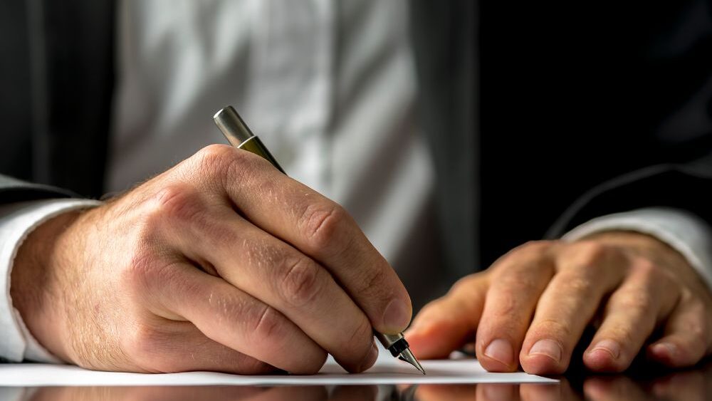 Man signing legal document with fountain pen