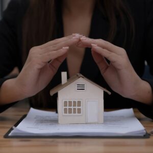 Hands shielding small model house on legal documents