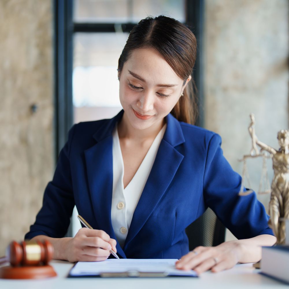 Female attorney in a blue blazer signing documents at her desk