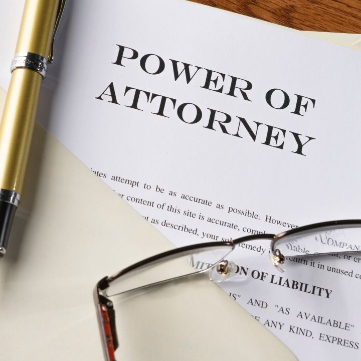 Close-up of a "Power of Attorney" document, a pen, and glasses on a desk