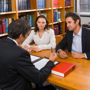 Attorney discussing trust documents with two clients at table in law office.