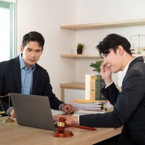 Two professionals reviewing documents and laptop during gift tax consultation.
